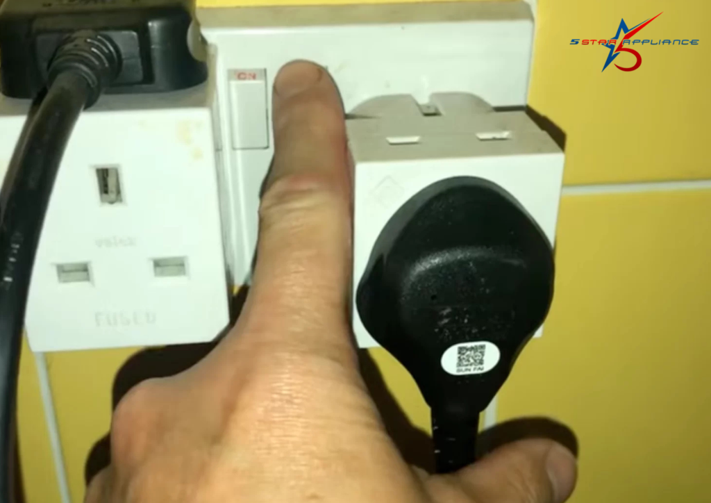Alt text: Turning off wall outlet before unplugging washing machine to fix drainage issue.