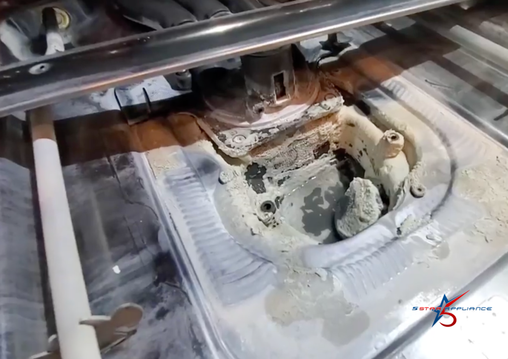 Severe hard water mineral buildup and calcium deposits inside a dishwasher's internal heating and pump housing.