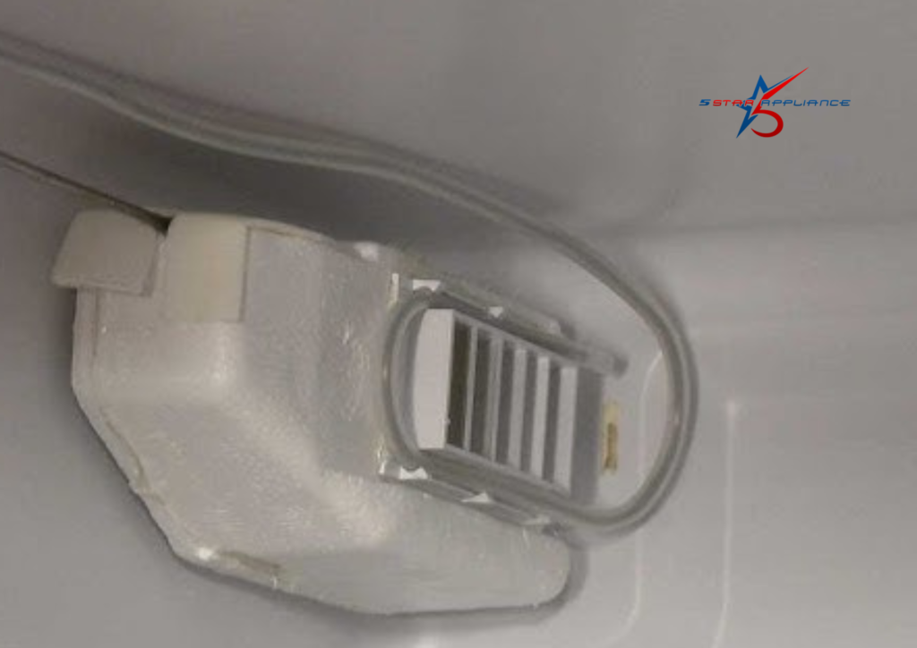 Close-up of a refrigerator air damper control assembly with white styrofoam insulation and a plastic vent, showing the internal mechanism that regulates airflow between the freezer and fridge sections.