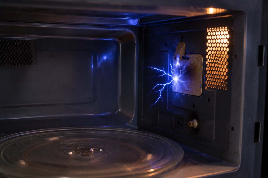 Blue electrical arc sparking near the interior side wall of a microwave oven