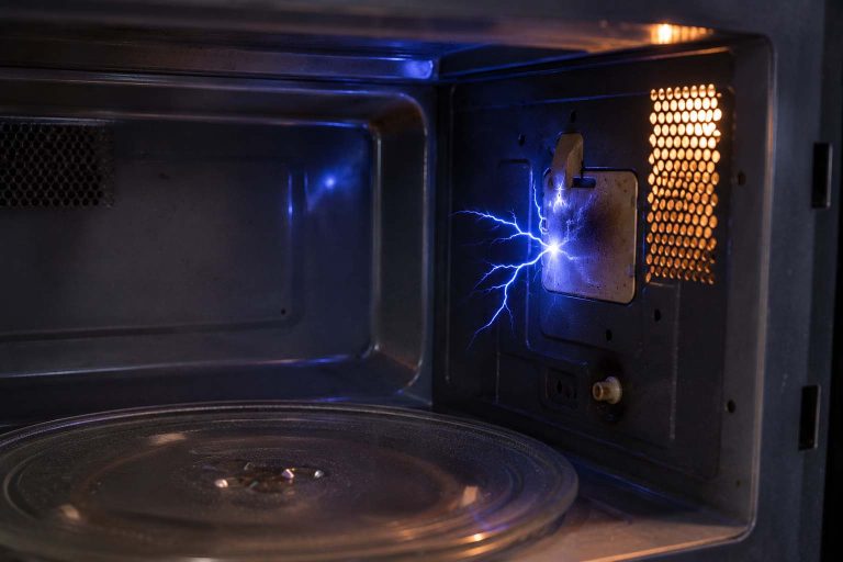 Blue electrical arc sparking near the interior side wall of a microwave oven
